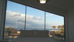 Una habitación con un ventanal grande que ofrece vistas al mar y árboles distantes.