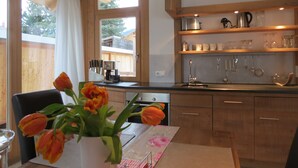 A kitchen with wooden cabinets, a coffee maker, and a vase with tulips on the counter. - Ferienwohnung Landhaus alpinum (Lenggries)