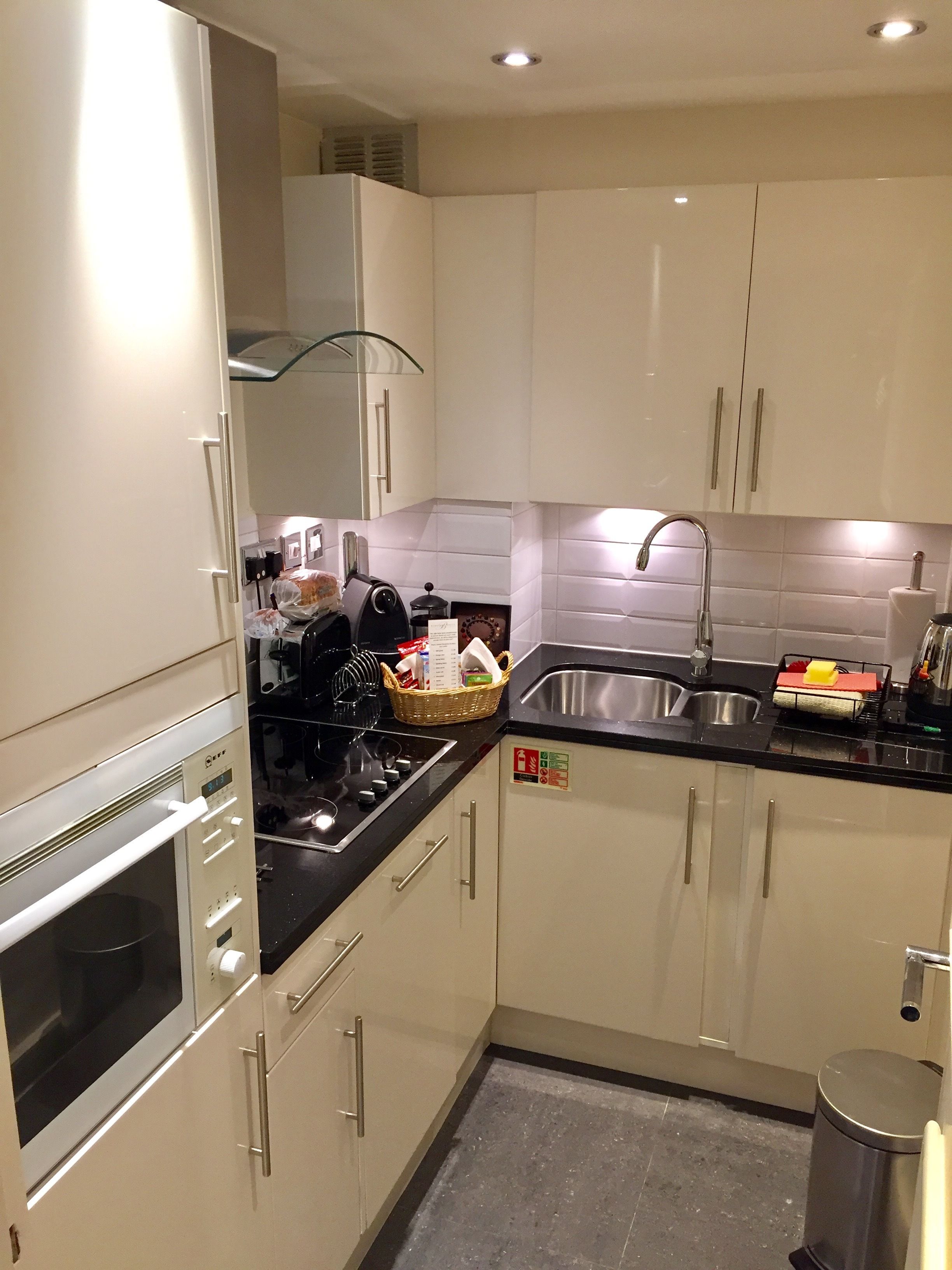 Een moderne keuken met witte kastjes, een zwart aanrecht, een roestvrijstalen spoelbak en een ingebouwde oven.
