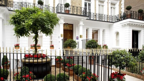 A traditional building with a white facade, a black iron fence, and potted plants. - Beaufort House - Knightsbridge (London)