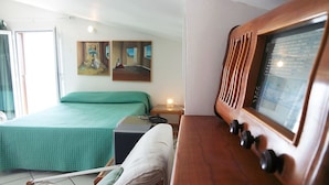 Una habitación con una cama, un armario de madera con televisor, y obras de arte en la pared.