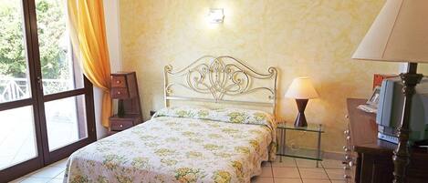 A bedroom with a bed, bedside lamps, a nightstand, and a window with curtains.