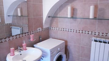 Un bagno con lavandino, lavatrice e specchio.