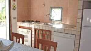 A compact kitchen with a gas stove, sink, and a window above the sink. - Villa Sarolli (Ascea)