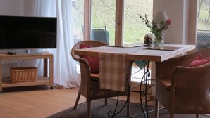 A dining area with a table, chairs, a television on a stand, and a view of the outdoors. - Mountainlodge Dorfhaus (Lenggries)
