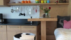 A kitchen with wooden cabinets, a black countertop, and a hanging utensil rack. - Mountainlodge Dorfhaus (Lenggries)