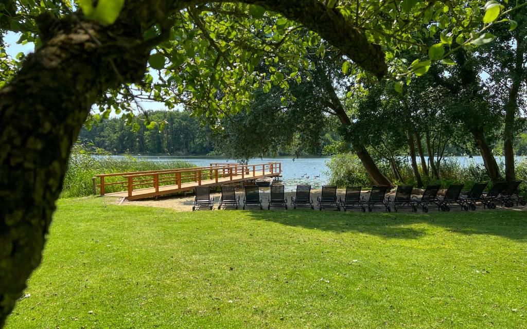 A lakeside park with a wooden deck, lounge chairs, and a grassy area.