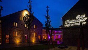 A brick building with illuminated windows and a neon sign reading "Zum Ritterstaler." - Hotel Zum Rittmeister (Werder (Havel))