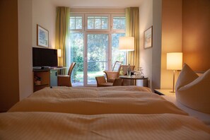A hotel room with a large bed, a desk, a chair, and a television.