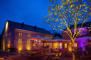 A stone building with outdoor seating and umbrellas, surrounded by trees. - Hotel Zum Rittmeister (Werder (Havel))