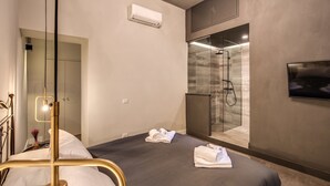 A modern hotel room with a bed, a TV, a shower, and an air conditioning unit. - St. Eligio Suite (Rome)
