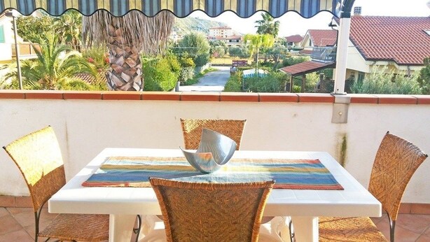 Un comedor con mesa y sillas, vista a una calle residencial y un patio cubierto.