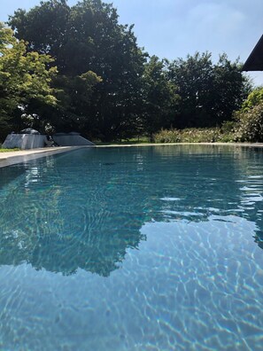 Una piscina al aire libre de temporada, sombrillas