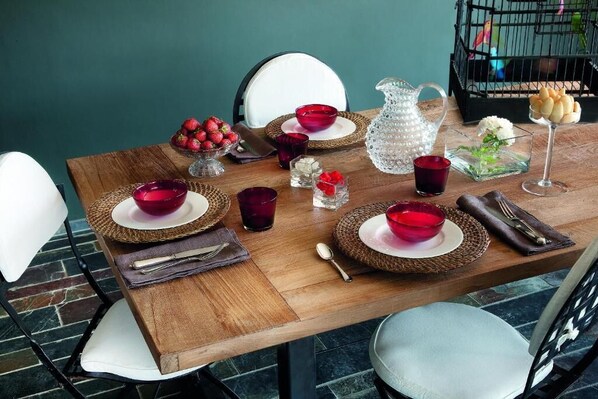 A wooden dining table set with red bowls, a pitcher, and a basket of strawberries. - B&B Puntodivista (Chieri)