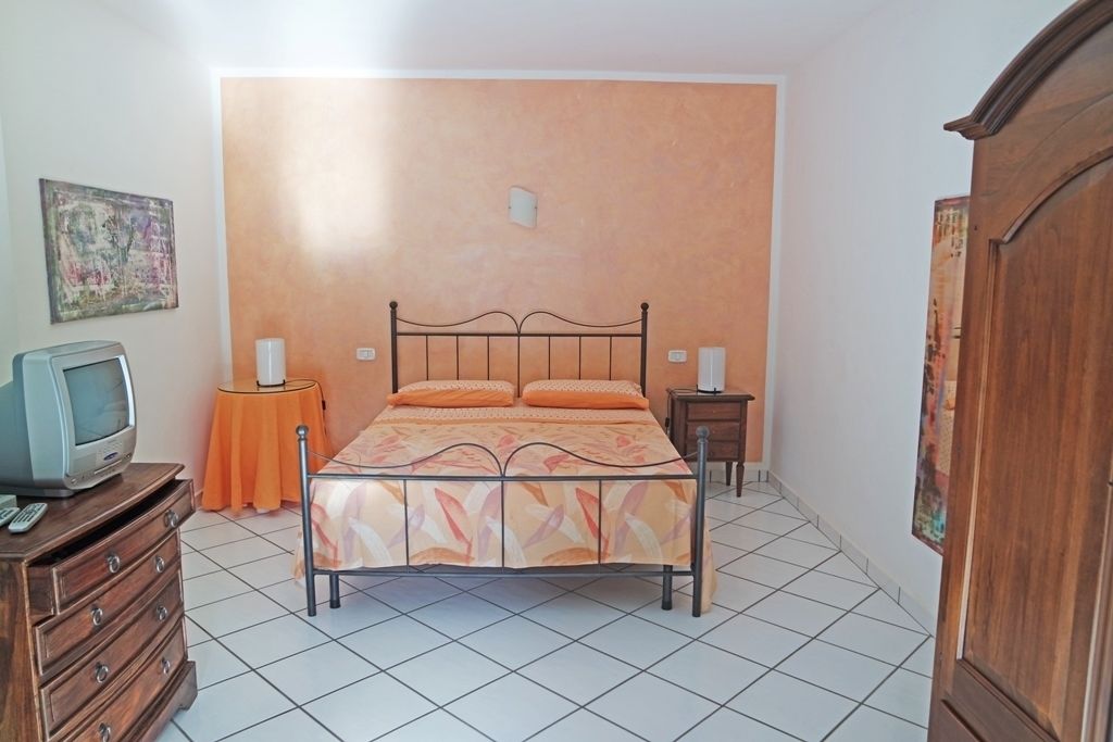 A bedroom with a bed, a dresser, a television, and a wall-mounted artwork.