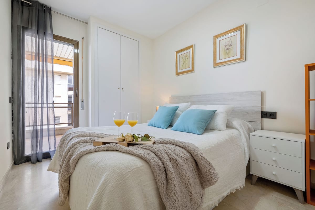 A bedroom with a bed, bedside table, and a window with curtains.