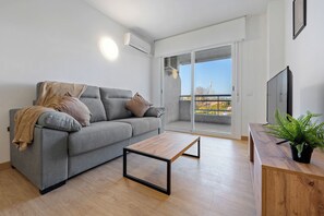 Ein modernes Wohnzimmer mit grauem Sofa, einem Holztisch und einem Balkon mit Blick.
