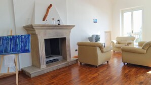A living room with a fireplace, beige sofas, and a painting on the wall. - Villa Sant'Antonio (Ascea)