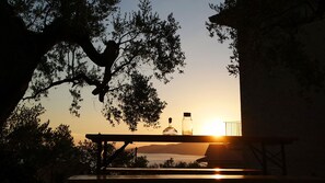 Tramonto visibile dal balcone, con un tavolo e due bottiglie.