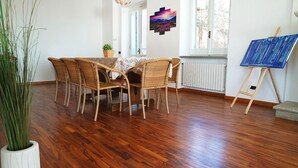 A dining area with a table and chairs, a potted plant, a painting on the wall, and an easel with a canvas. - Villa Sant'Antonio (Ascea)