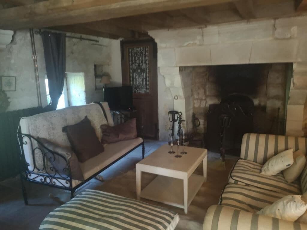 Een gezellige woonkamer met een stenen openhaard, een bank, een gestreept fauteuil en een salontafel.