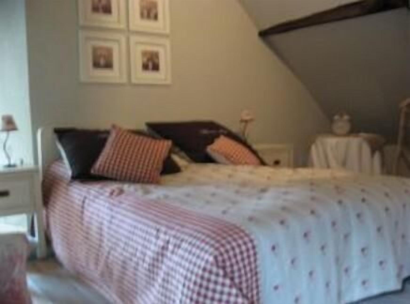 Ein Schlafzimmer mit einem Bett, Kissen, einem Nachttisch und einem kleinen Tisch.