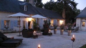 A courtyard with outdoor seating, a dog, and lit candles. - Chambres d'Hôtes Le Mouton (Blaison-Saint-Sulpice)