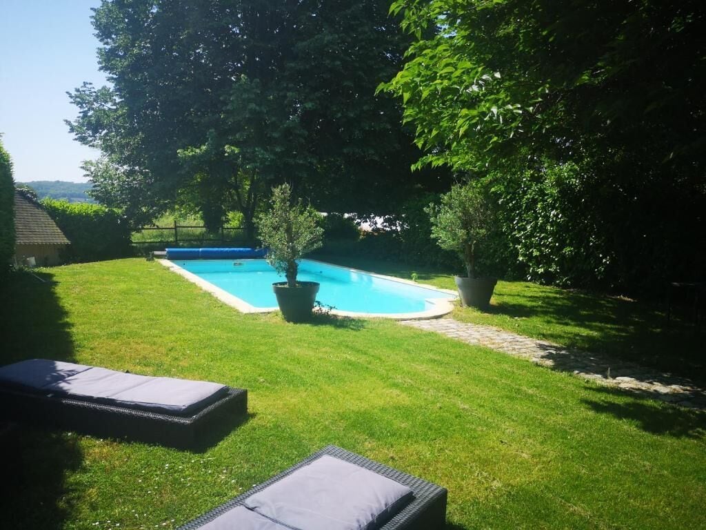 En baghave med swimmingpool, to liggestole og et lille træ.