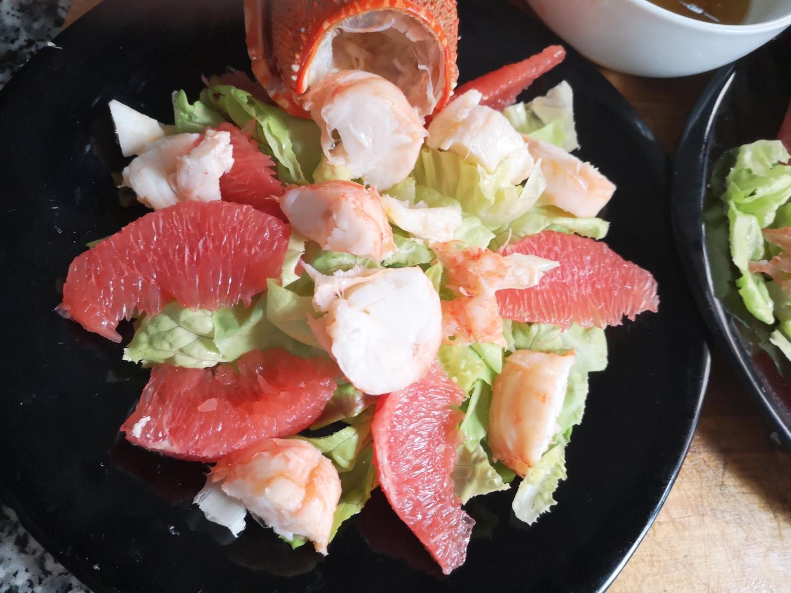 A plate of salad with lettuce, shrimp, and grapefruit segments.