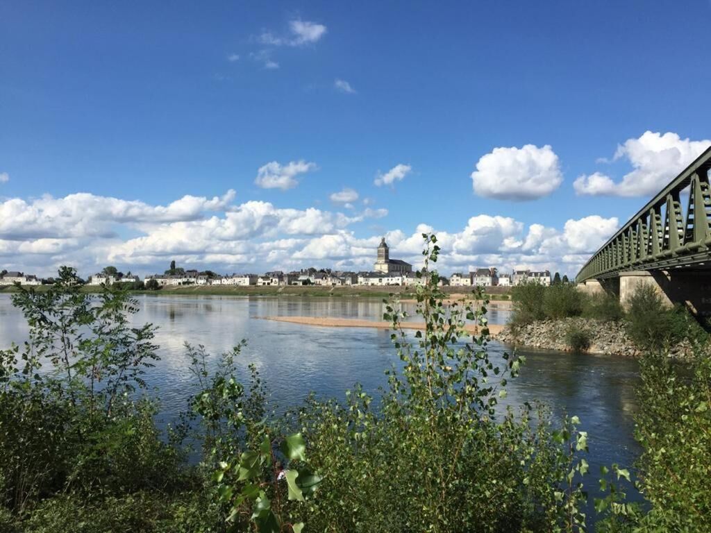 A river with a bridge, a town in the background, and a clear sky.