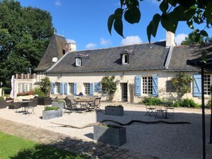 A traditional building with a gravel courtyard, outdoor seating, and a stone pathway. - Chambres d'Hôtes Le Mouton (Blaison-Saint-Sulpice)