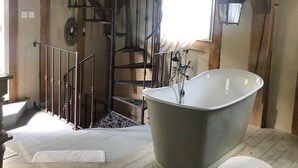 A rustic bathroom with a freestanding bathtub, a wooden staircase, and a vintage-style lantern. - Chambres d'Hôtes Le Mouton (Blaison-Saint-Sulpice)