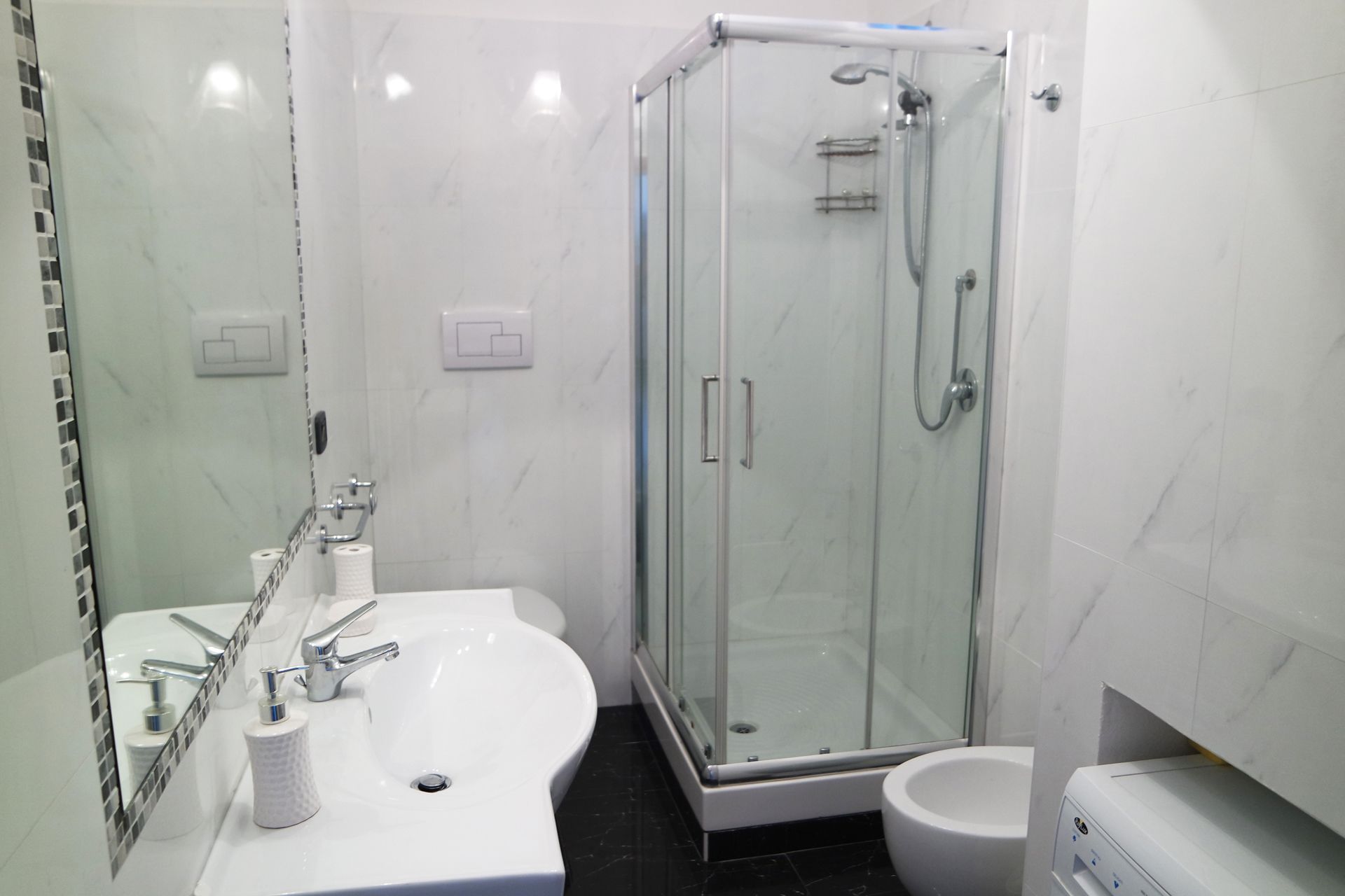 A modern bathroom with a glass-enclosed shower, a white sink with a mirror, and a toilet.