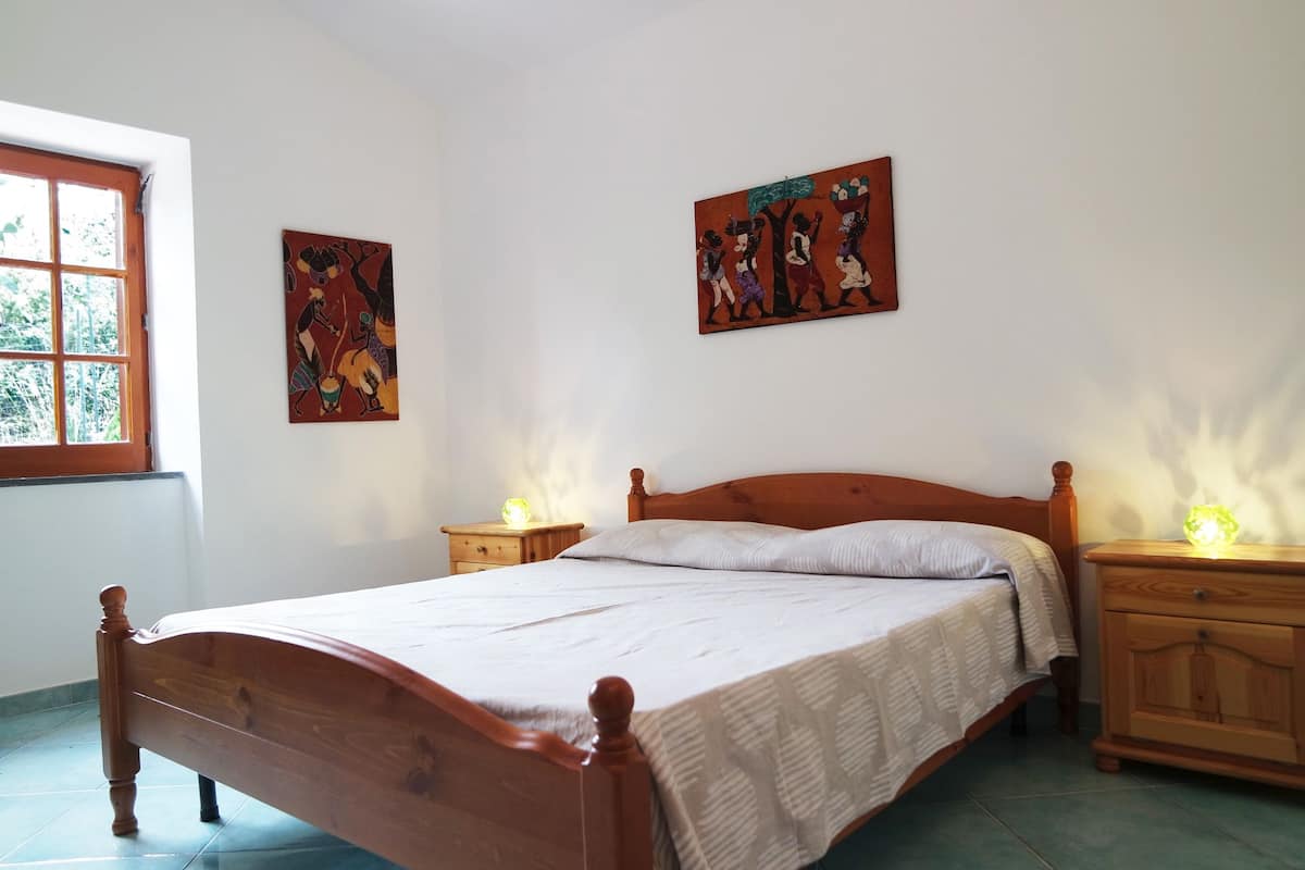 Un dormitorio con una cama de madera, dos mesitas de noche y dos cuadros colgados en la pared.