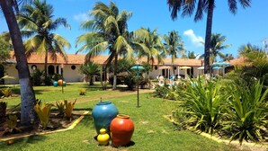 A courtyard with palm trees, a swimming pool, and a building with a tiled roof. - Hotel Praia Do Conde (Conde)