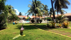 A tropical resort with a swimming pool, lounge chairs, and palm trees. - Hotel Praia Do Conde (Conde)
