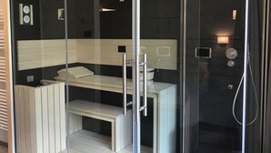 Un baño moderno con cabina de ducha de vidrio, tocador blanco y perchero.