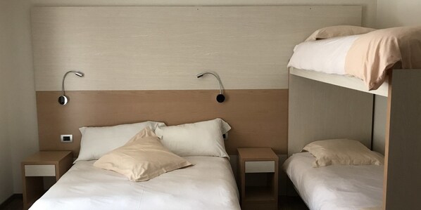 Una habitación de hotel con una cama nido, dos mesitas de noche y un cabecero.