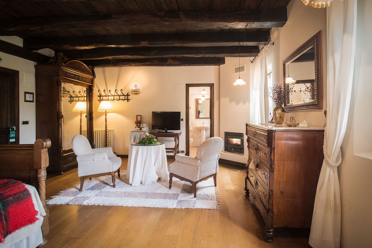 A cozy room with wooden furniture, a fireplace, a television, and a mirror.