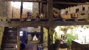 A rustic dining area with a fireplace, wooden beams, stone walls, and a high ceiling. - Caserio Iruaritz (Amurrio)