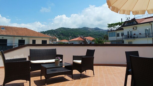 Una terraza con mobiliario de mimbre, una mesa y una sombrilla.