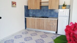 Una cocina compacta con armarios de madera, estufa a gas y refrigerador blanco.