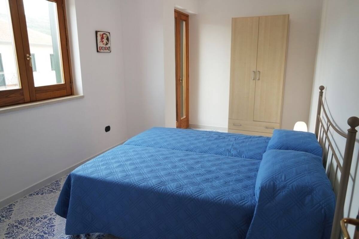A bedroom with a bed, a wardrobe, a door, and a window.
