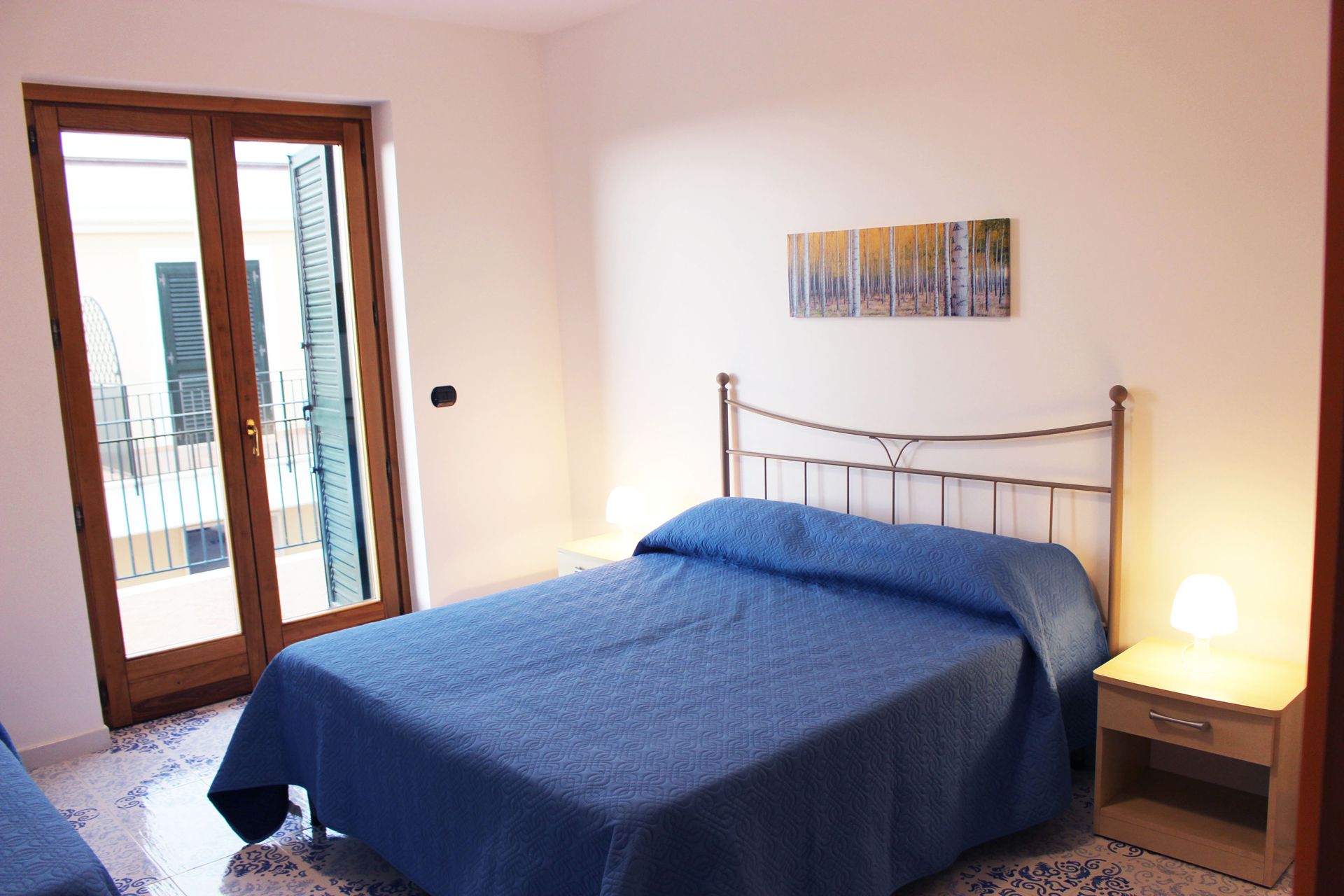 Un dormitorio con una cama, mesitas de noche y un cuadro en la pared.
