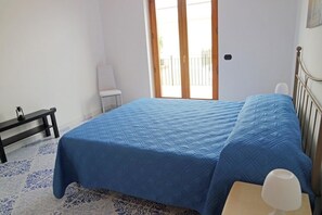 Un dormitorio con cama, mesita de noche, una silla y ventana con vistas.