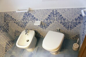 Un baño con bidé, inodoro y azulejos estampados.