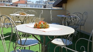 A rooftop terrace with round tables and metal chairs, featuring a decorative centerpiece. - B&B Jolie Center (Pescara)