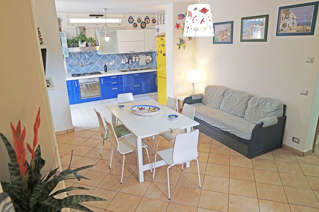 A compact living space with a dining area, kitchenette, and a sofa.