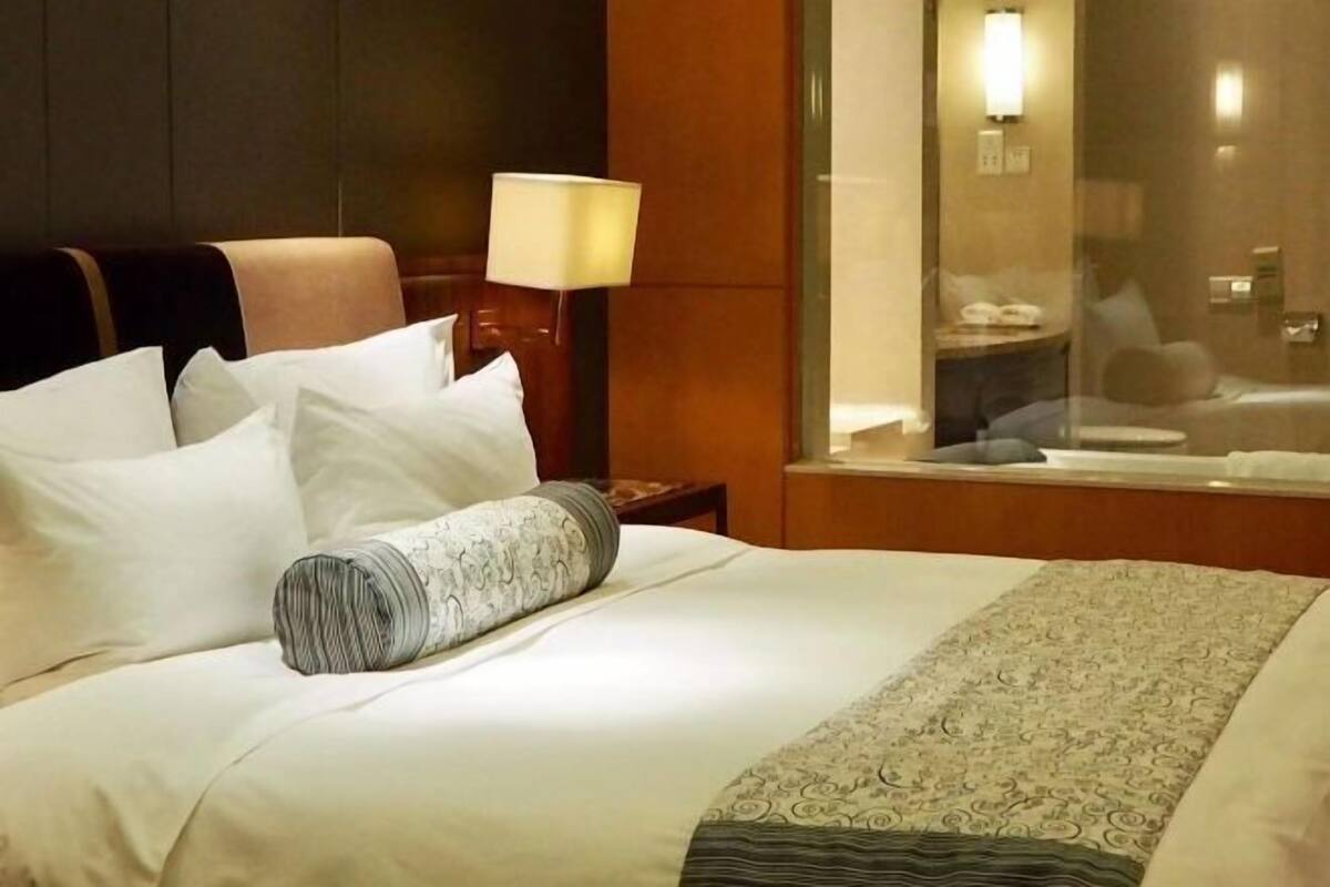 A hotel room with a bed, a lamp, a nightstand, and a window.