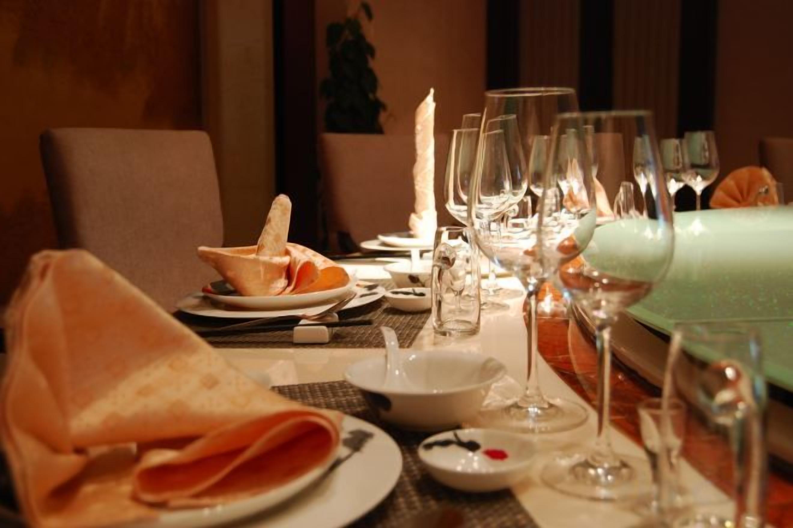 A dining table set with plates, glasses, and a folded napkin.